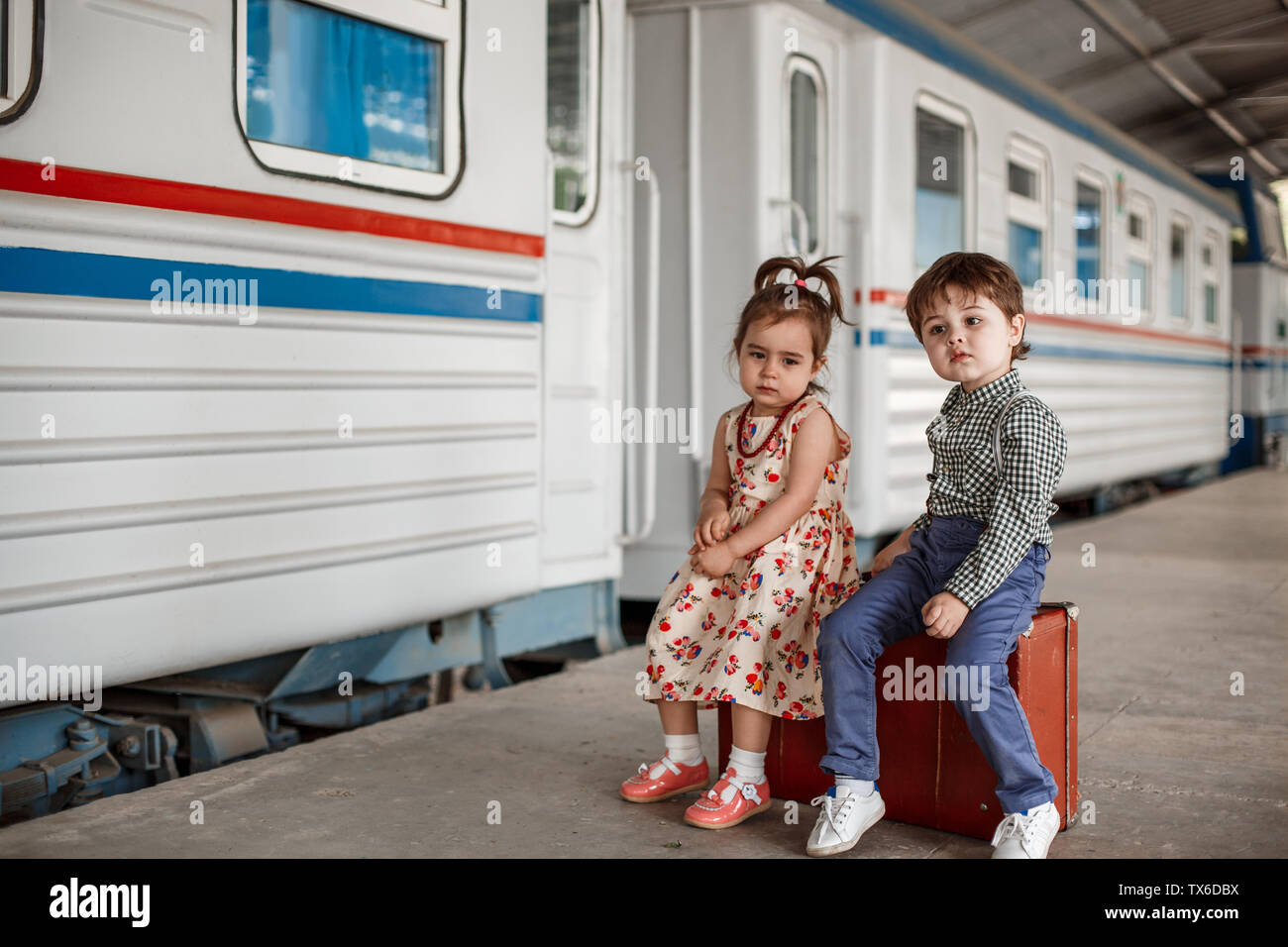 Chico y chica en vintage vintage ropa con la maleta en la pequeña estación  de tren Fotografía de stock - Alamy