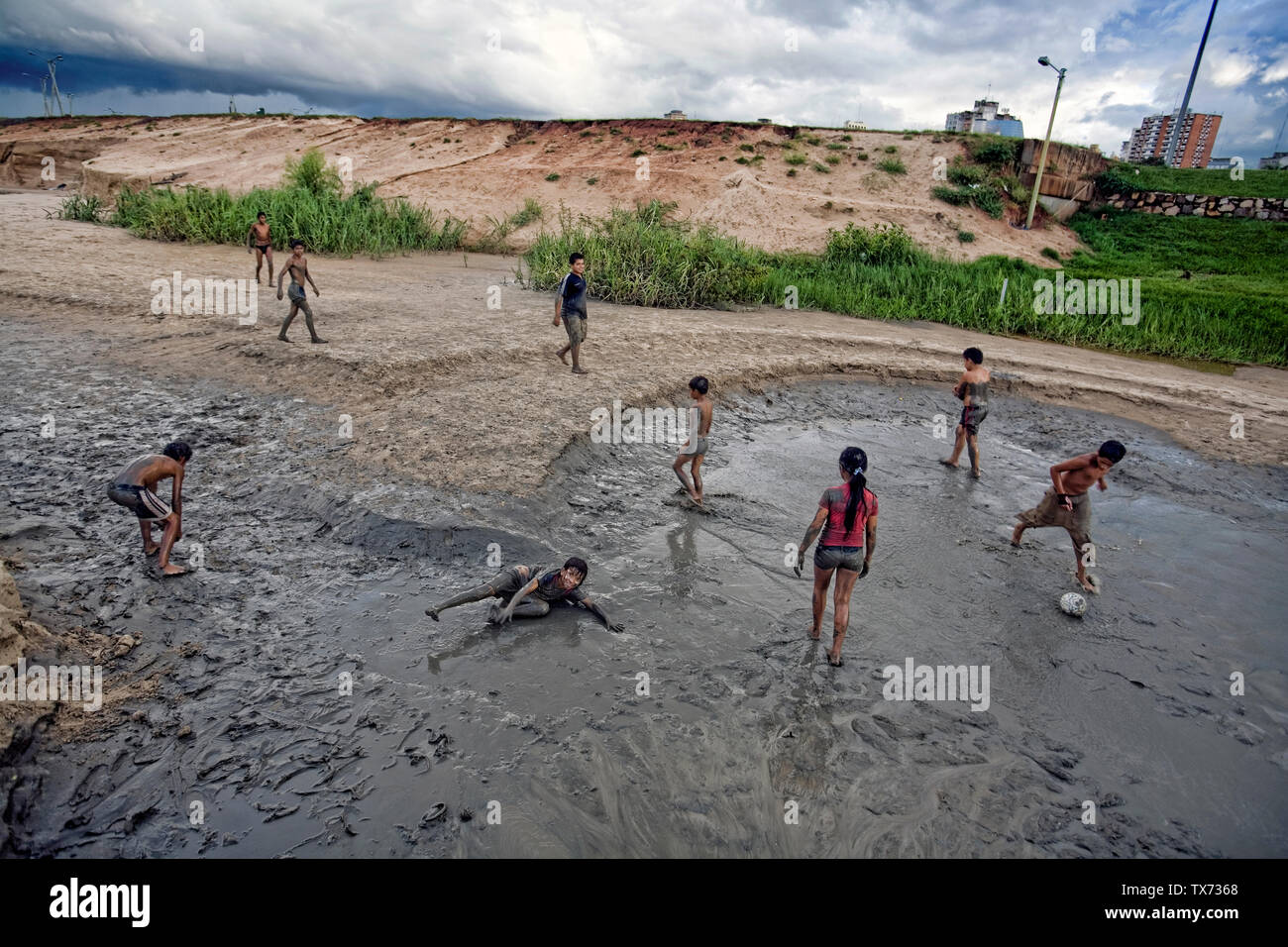 Un grupo de niños jugando al fútbol en torno a un tubo de agua roto, Asunción, Paraguay Foto de stock