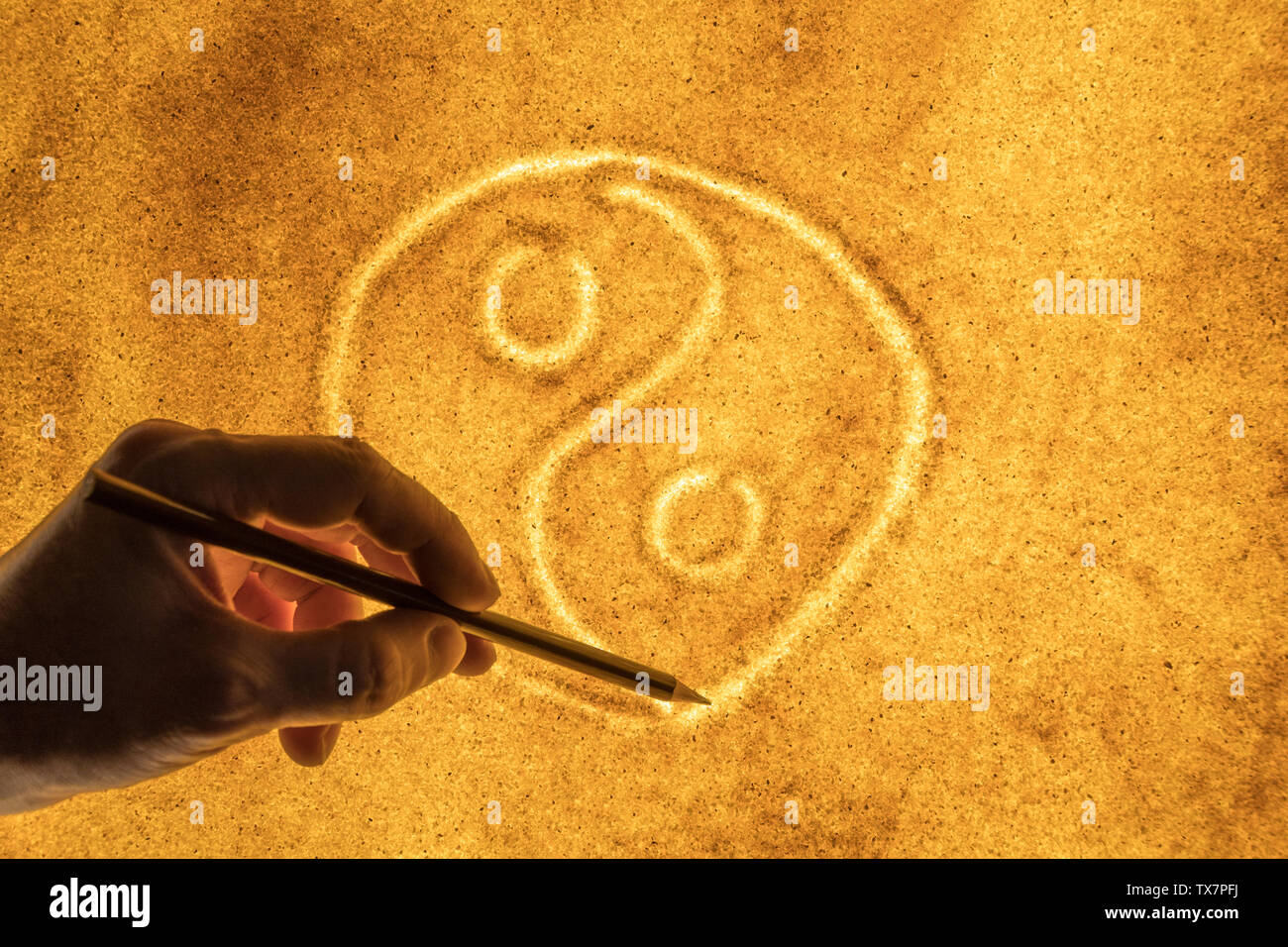 Las manos de los hombres, dibujar en la arena un símbolo del Yin Yang el concepto de armonía. Foto de stock