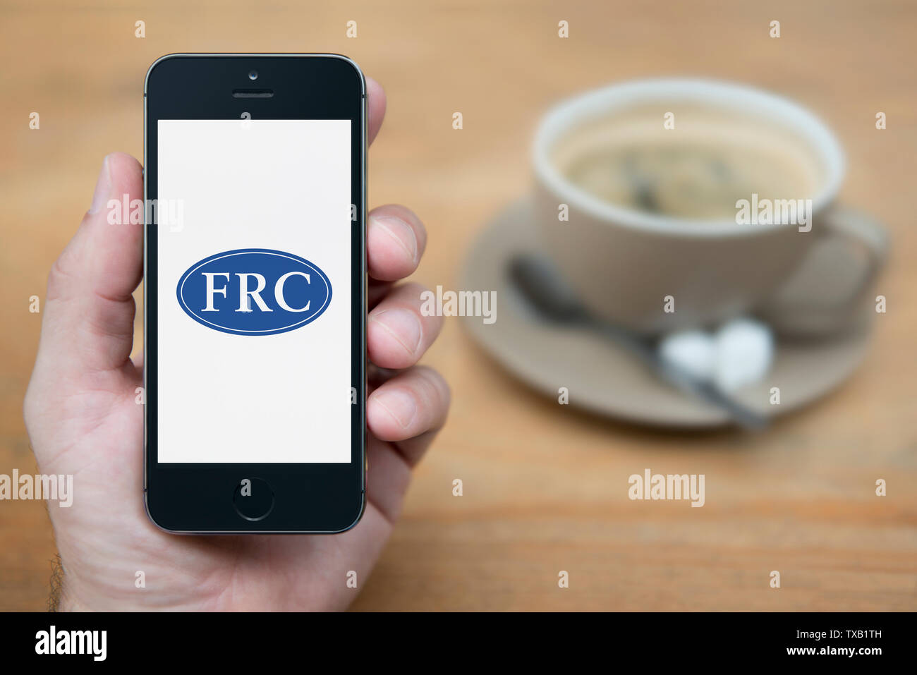 Un hombre mira el iPhone que muestra el Consejo de Informes Financieros (FRC) logotipo (uso Editorial solamente). Foto de stock