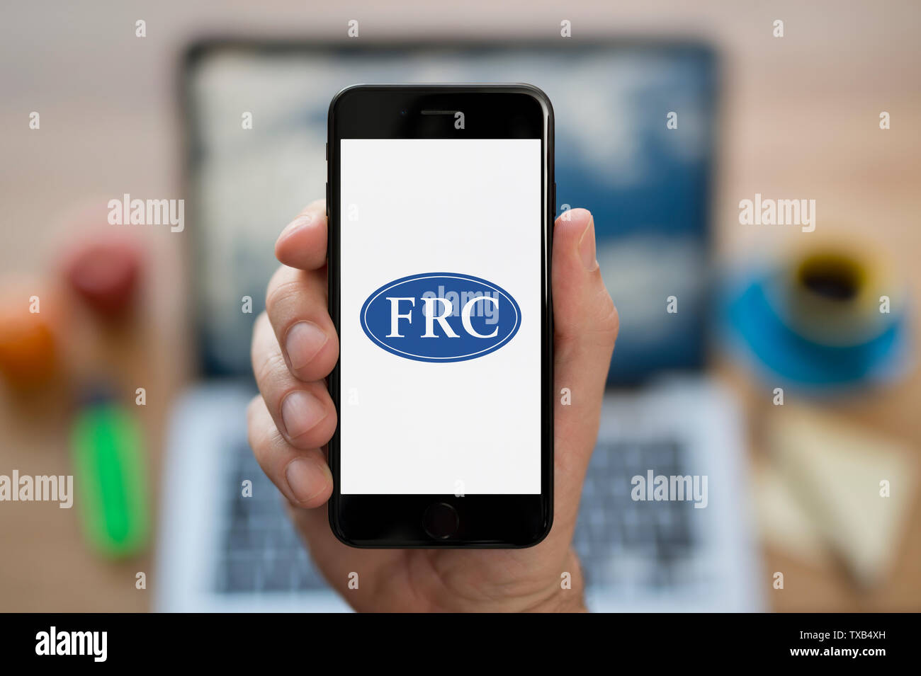 Un hombre mira el iPhone que muestra el Consejo de Informes Financieros (FRC) logotipo (uso Editorial solamente). Foto de stock