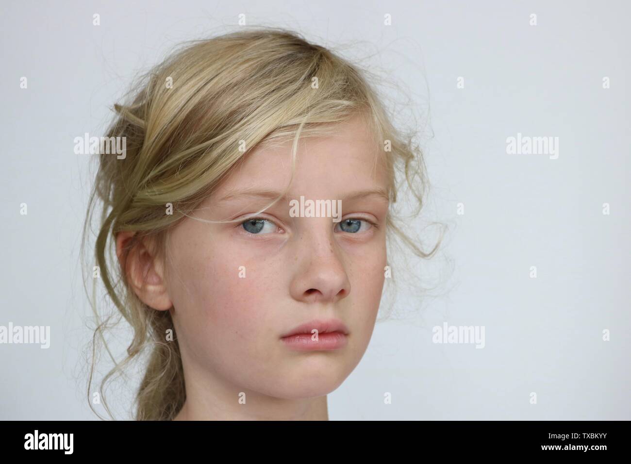 Retrato de una niña pre adolescente infeliz mirando la cámara sobre un fondo blanco. Foto de stock