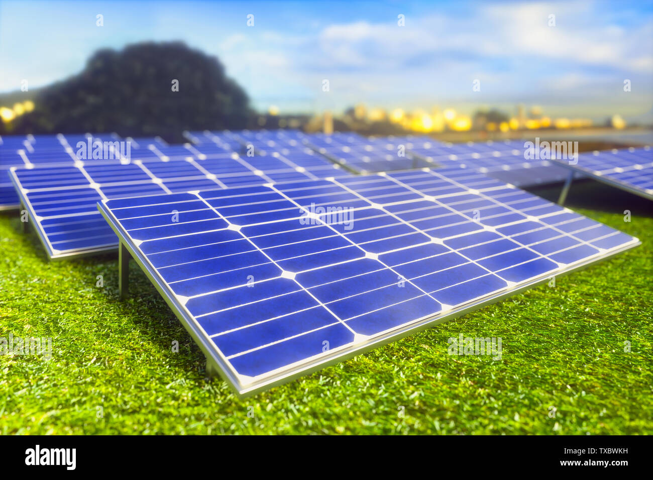 Paneles solares repartidos en el campo sobre la hierba verde. En el fondo de la ciudad para que la energía está proporcionada. Foto de stock