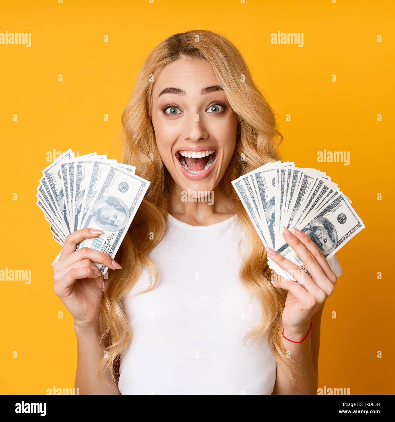 Emocionada Chica sujetando el dinero billetes sobre fondo amarillo, Cultivo Foto de stock