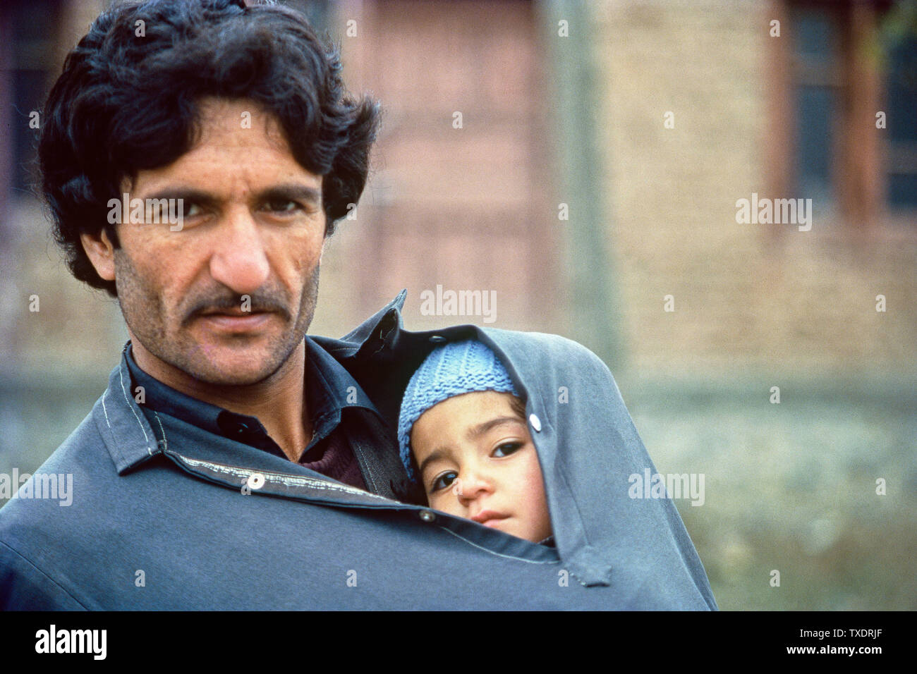 Niño cuddles dentro de padre bata caliente durante el invierno, Srinagar, Cachemira, India, Asia Foto de stock