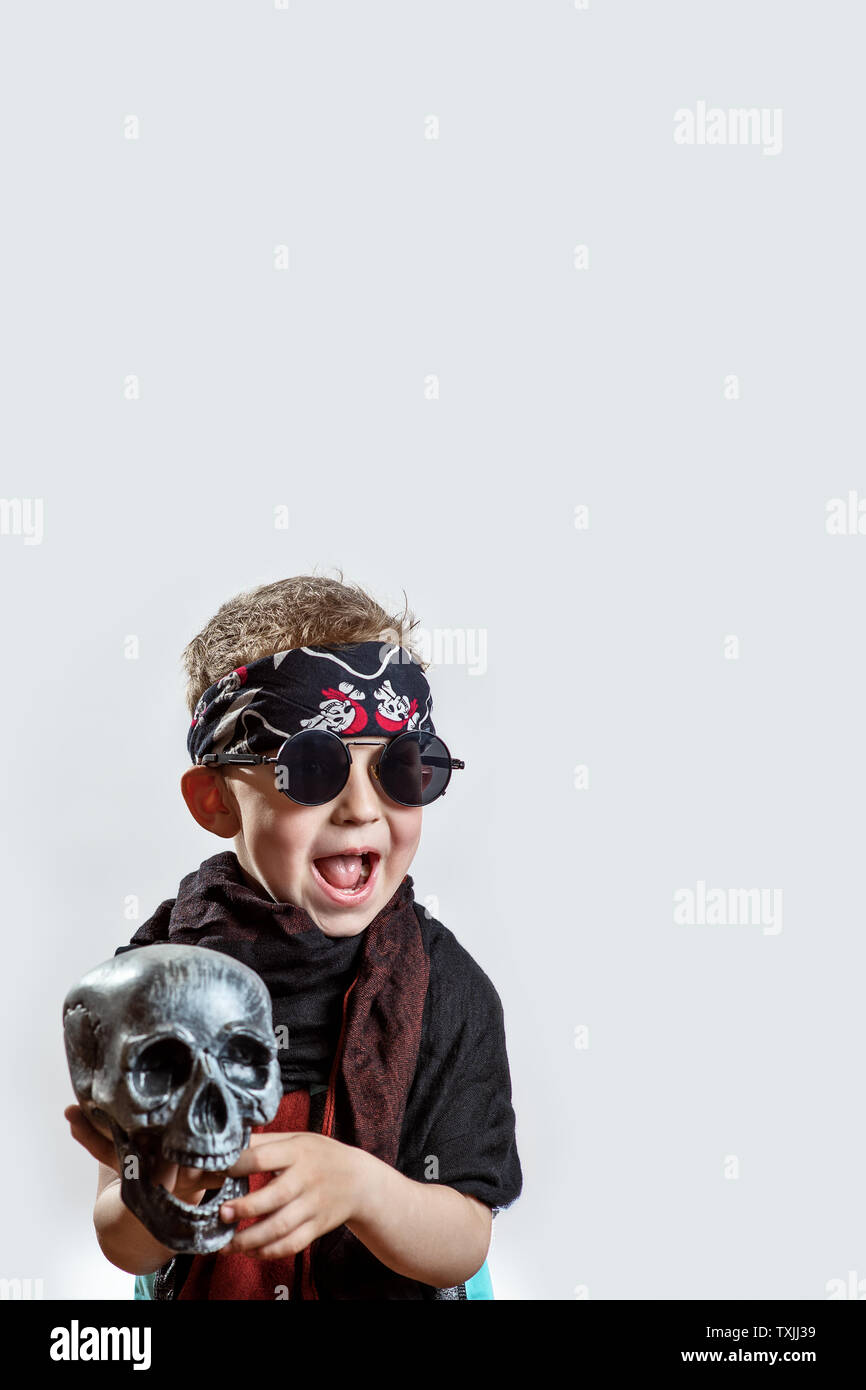 Chico rockero en gafas negras, bufanda, pañuelo y con una calavera en sus  manos sobre un fondo de luz Fotografía de stock - Alamy