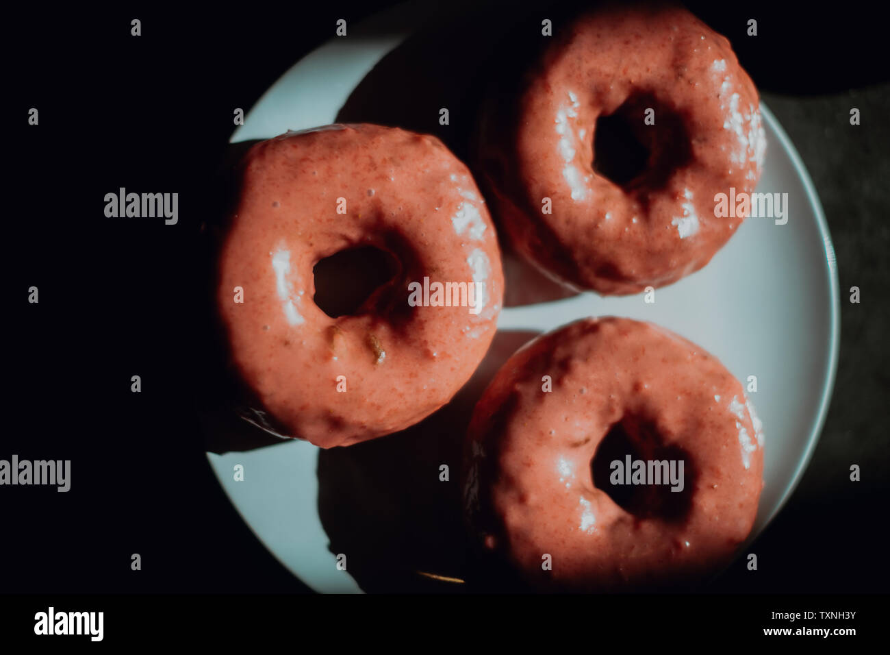 Tres agujeros de donut helado en la mesita de café, low key vista aérea Foto de stock