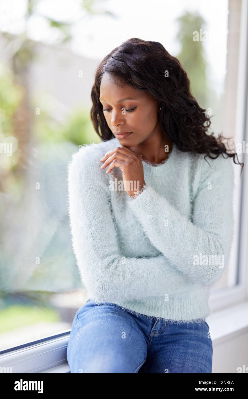 Mujer mirando étnicos triste sentado en una ventana Foto de stock