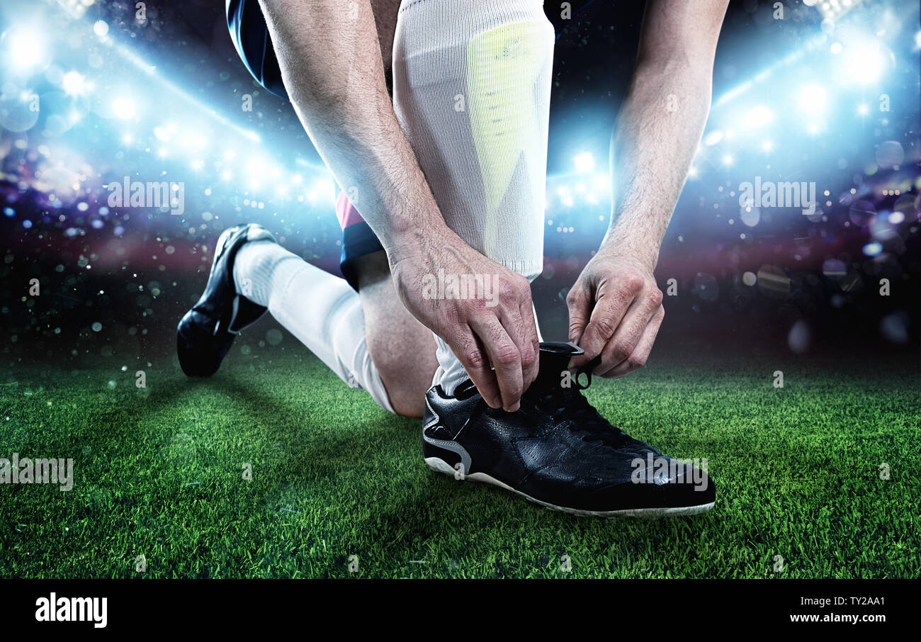 El jugador de fútbol ajustar sus zapatos antes del partido Foto de stock