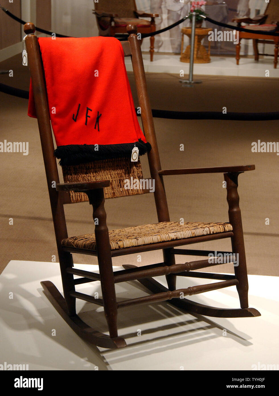 Una gira de roble y pintado de marrón sillón mecedora Kennedy llamó un  "Rocker" con una franela de lana roja JFK monogramed cobija fue subastado  junto con otros elementos de las viviendas