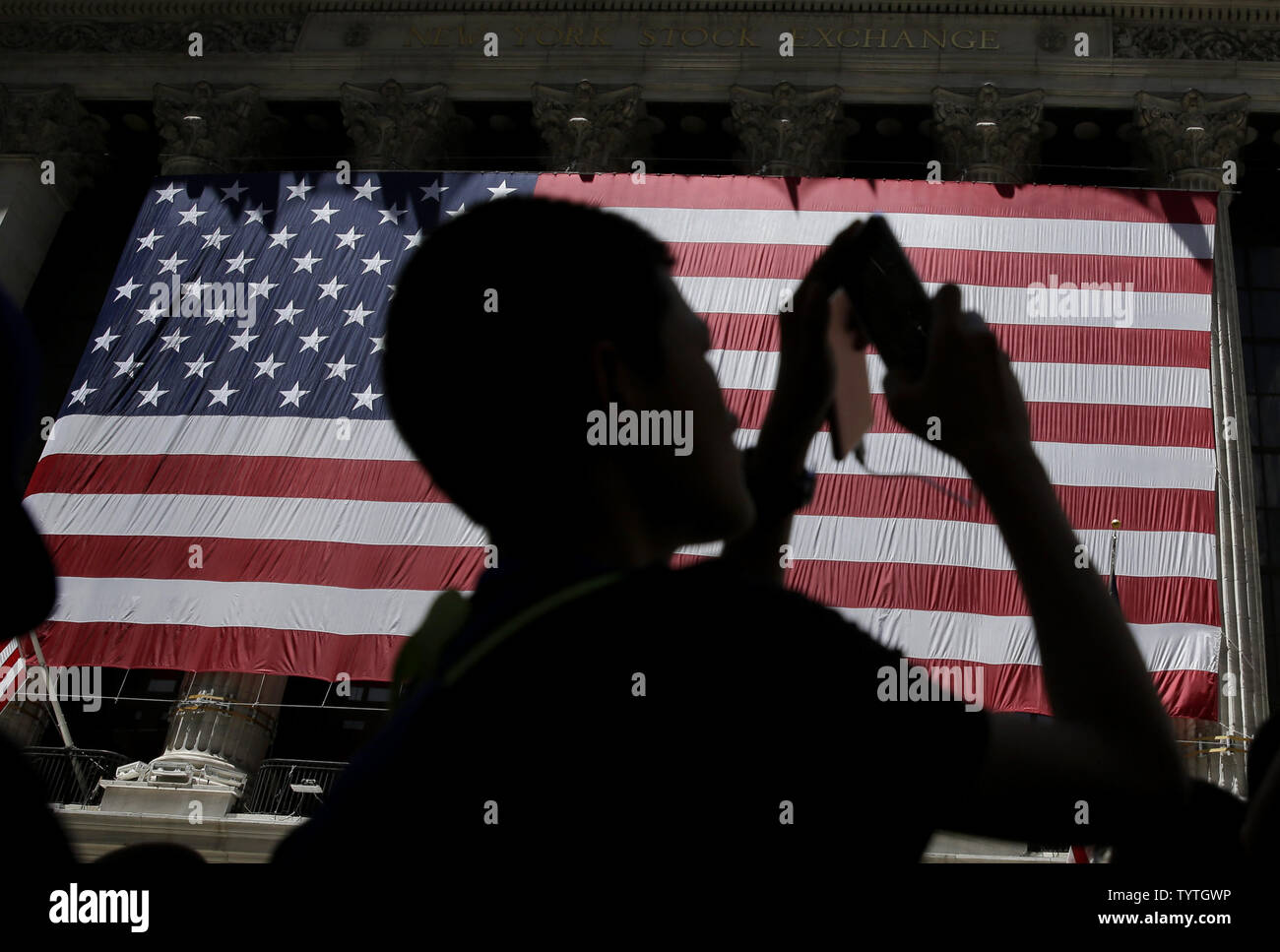 Un niño toma una foto donde fuera una gigantesca bandera americana que  cuelga en el NYSE antes del cierre de la campana de la Bolsa de Nueva York  en Wall Street, en