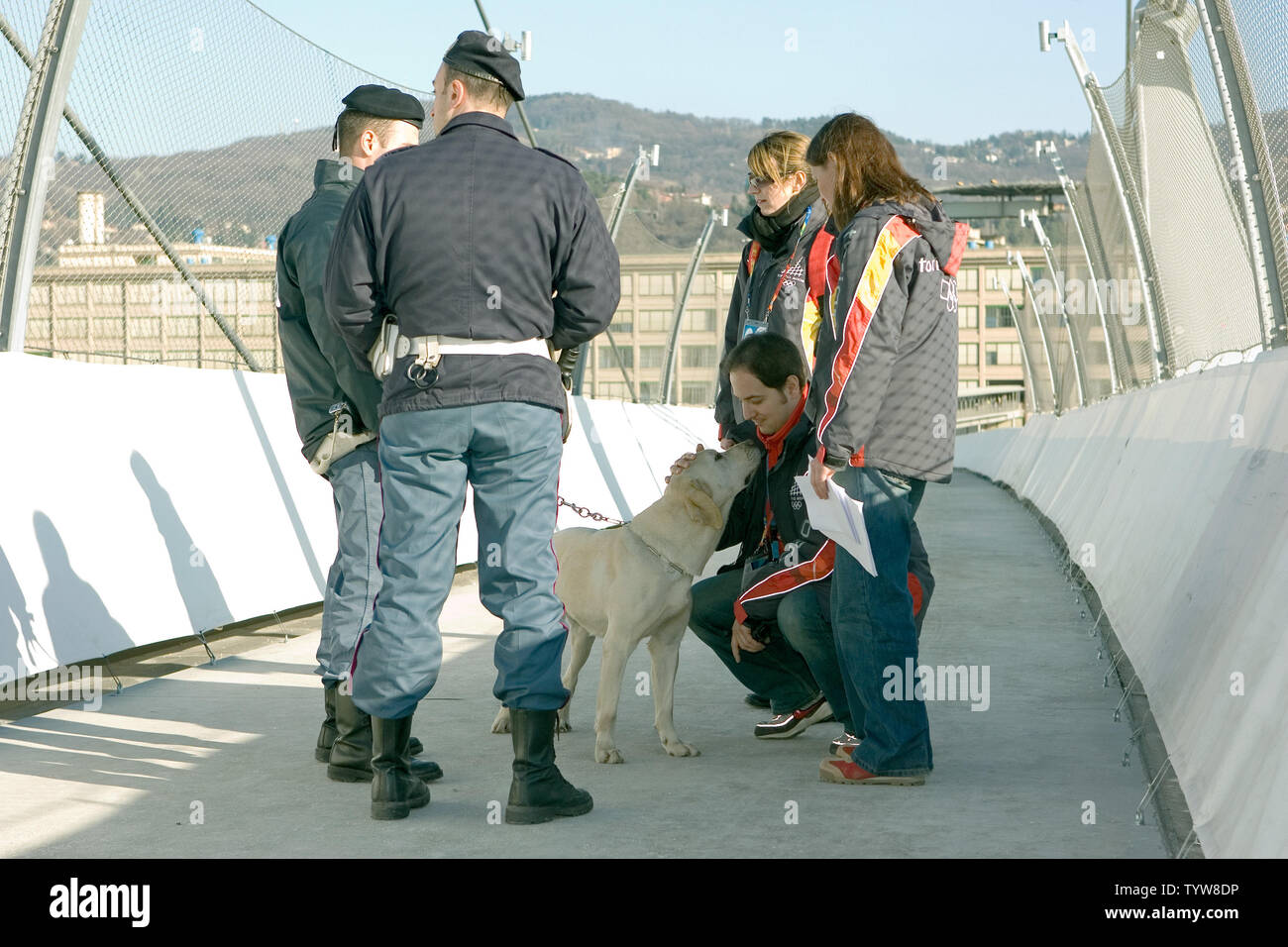 La policía de seguridad con un perro interactuar con los juegos olímpicos de los voluntarios en el puente que une la Aldea de Atletas con el Lingotto principales centros multimedia en Torino, Italia el inicio de los Juegos Olímpicos de Invierno de 2006, 9 de febrero de 2006. (UPI foto/Heinz Ruckemann) Foto de stock