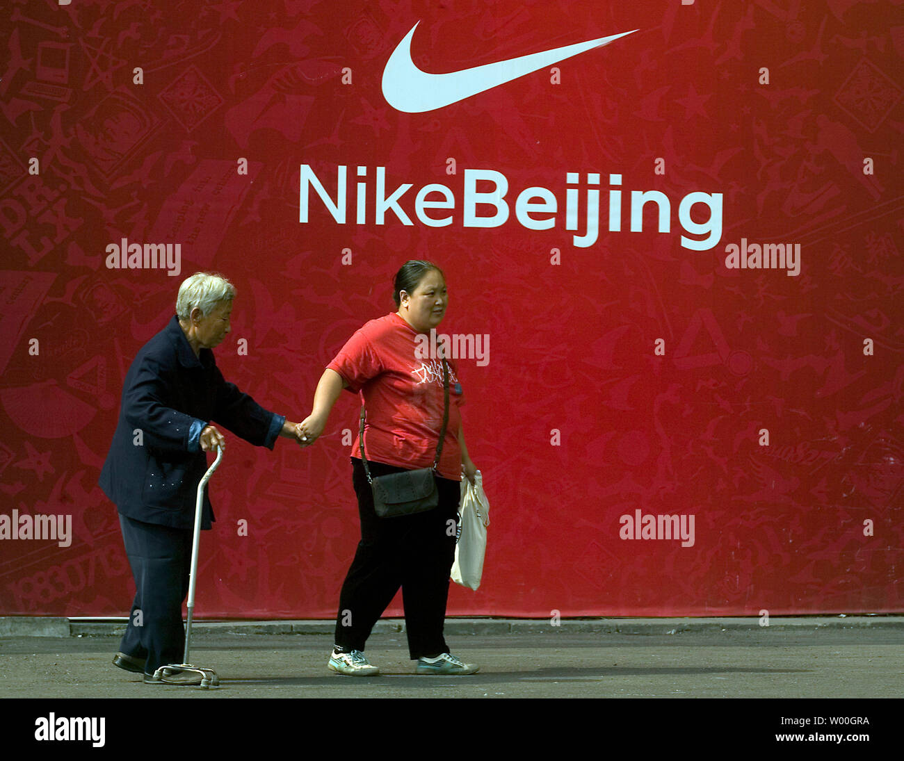 Una mujer china escoltas a una anciana delante de un anuncio de Nike fuera  de un centro comercial en Beijing, China el 9 de octubre de 2007. Los  Juegos Olímpicos de Beijing