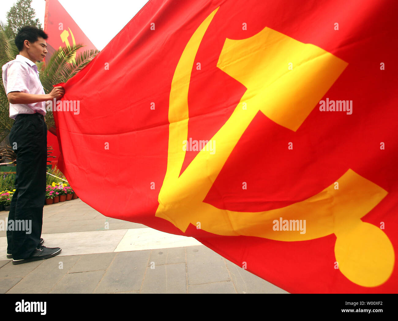 hombre chino sujeta el extremo de un gran Partido Comunista bandera durante celebración al aire libre en el camino hasta el 1 julio, el 90º aniversario de la fundación