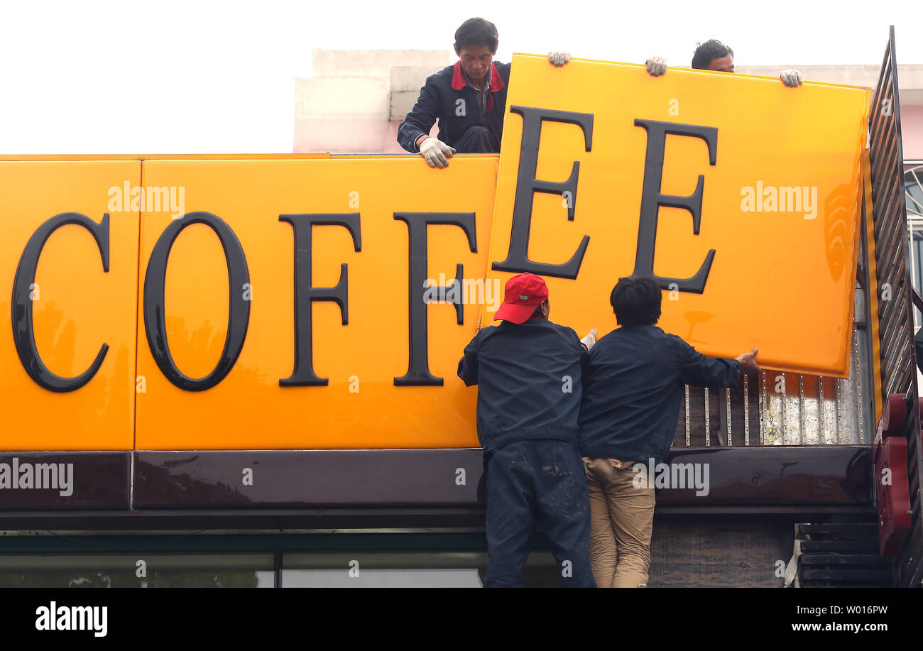 Los trabajadores chinos reunir un gran 'café' a firmar que adornan la fachada de un recién inaugurado café cafe en Beijing el 27 de noviembre de 2014. Miles de cafeterías especializadas en café, en lugar de copiar y té Starbucks' exitoso modelo de negocio, están abriendo en toda China. Starbucks' apuesta por convertir a millones de bebedores de té en los bebedores de café ha pagado enormes dividendos para el café, con sede en EE.UU. gigante. UPI/Stephen afeitadora Foto de stock