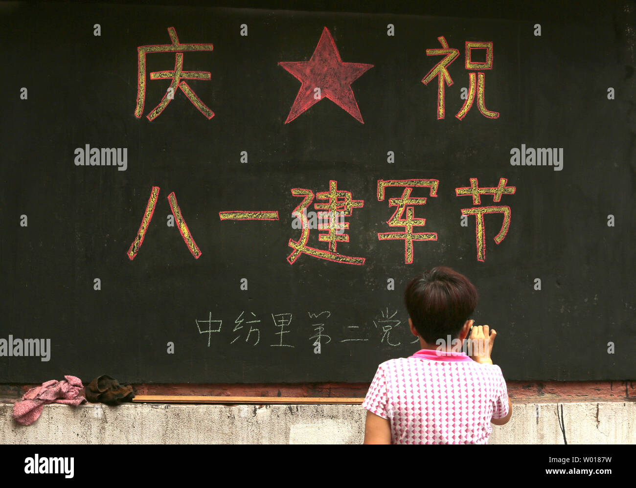 Una mujer china escribe un aviso patriótico para la conmemoración del 70º aniversario de la victoria de China contra la agresión japonesa en un barrio de Blackboard en Beijing el 9 de agosto de 2015. China celebrará un desfile militar masiva en septiembre. Foto por Stephen afeitadora/UPI Foto de stock