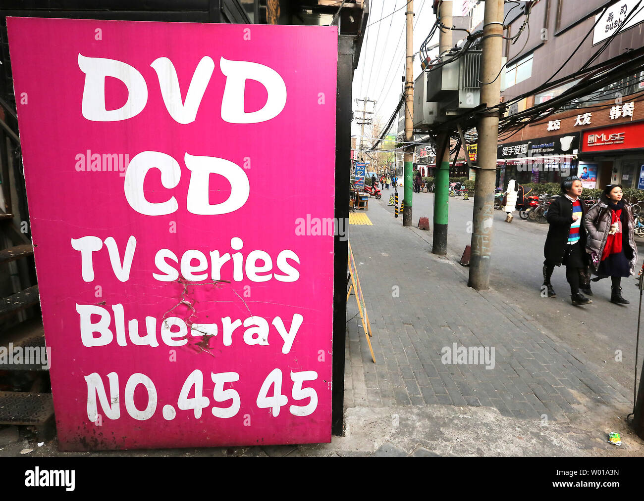 Chino pasa por una tienda de venta de DVDs y CDs pirateados de populares  películas, música y televisión en Beijing el 20 de enero de 2016. A pesar  de las continuas batallas