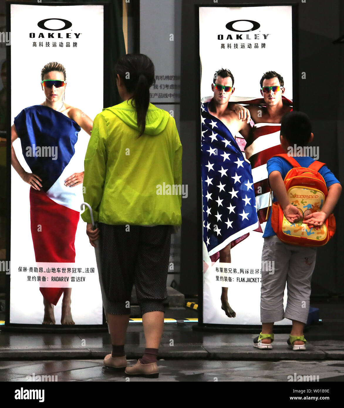 Una mujer china y su hijo mira una serie de anuncios de gafas de sol Oakley  con atletas olímpicos, envueltos en la bandera de su país en Beijing el 23  de julio
