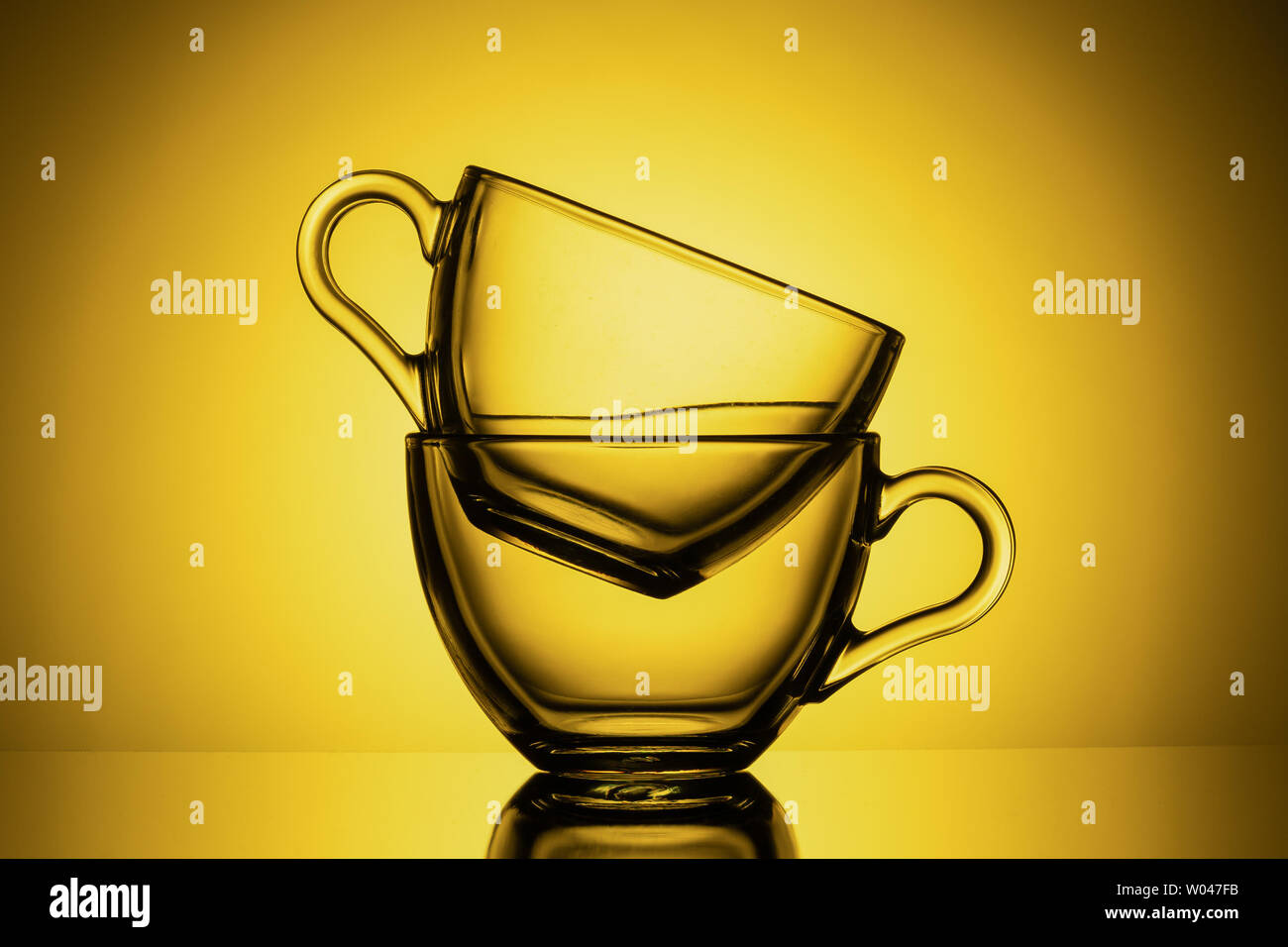 Dos tazas de cristal transparente para el té. Fondo amarillo, close-up, diseño horizontal Foto de stock