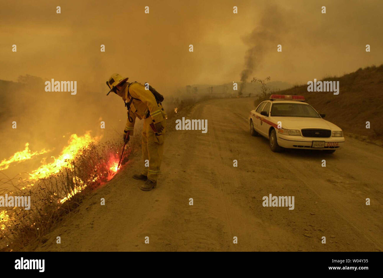Chula Vista bombero del Departamento de Bomberos de Dustin Dauber establece petardea en esperanzas de detener un incendio que amenaza la parte oriental de la Ciudad de Chula Vista, California, una ciudad en el condado de San Diego, 27 de octubre de 2003. Como los incendios forestales continúan ardiendo fuera de control en numerosas zonas de todo el condado carbonizando más de 100.000 acres y la quema de más de 500 estructuras y matando al menos a 13 personas. (UPI/Earl S. Cryer) Foto de stock