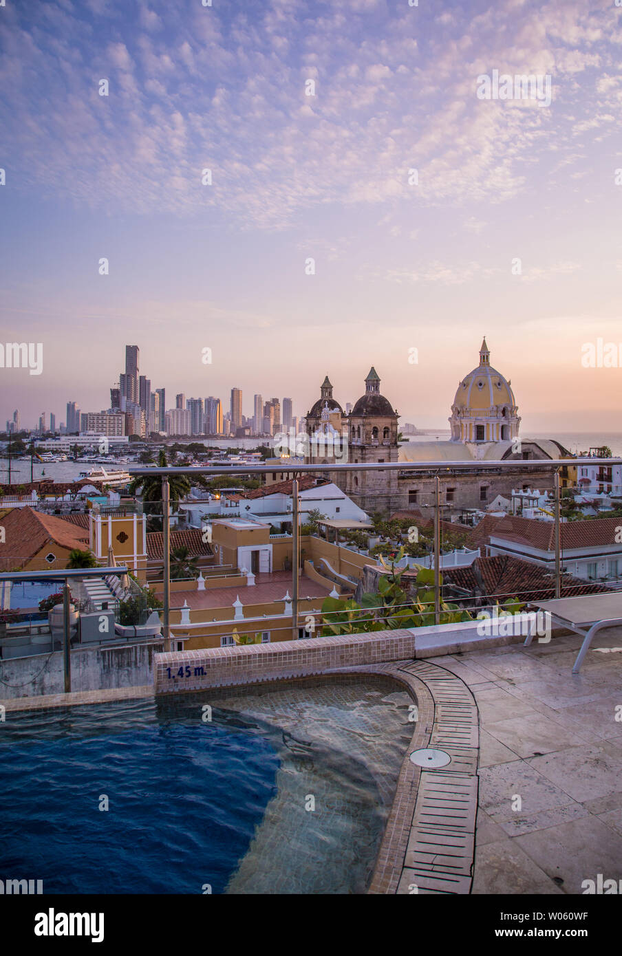 El sol se pone por encima de los tejados y el horizonte de la ciudad de Cartagena de Indias, Colombia - vista desde la terraza de la piscina y el bar de uno de los muchos hoteles de lujo del centro. Foto de stock