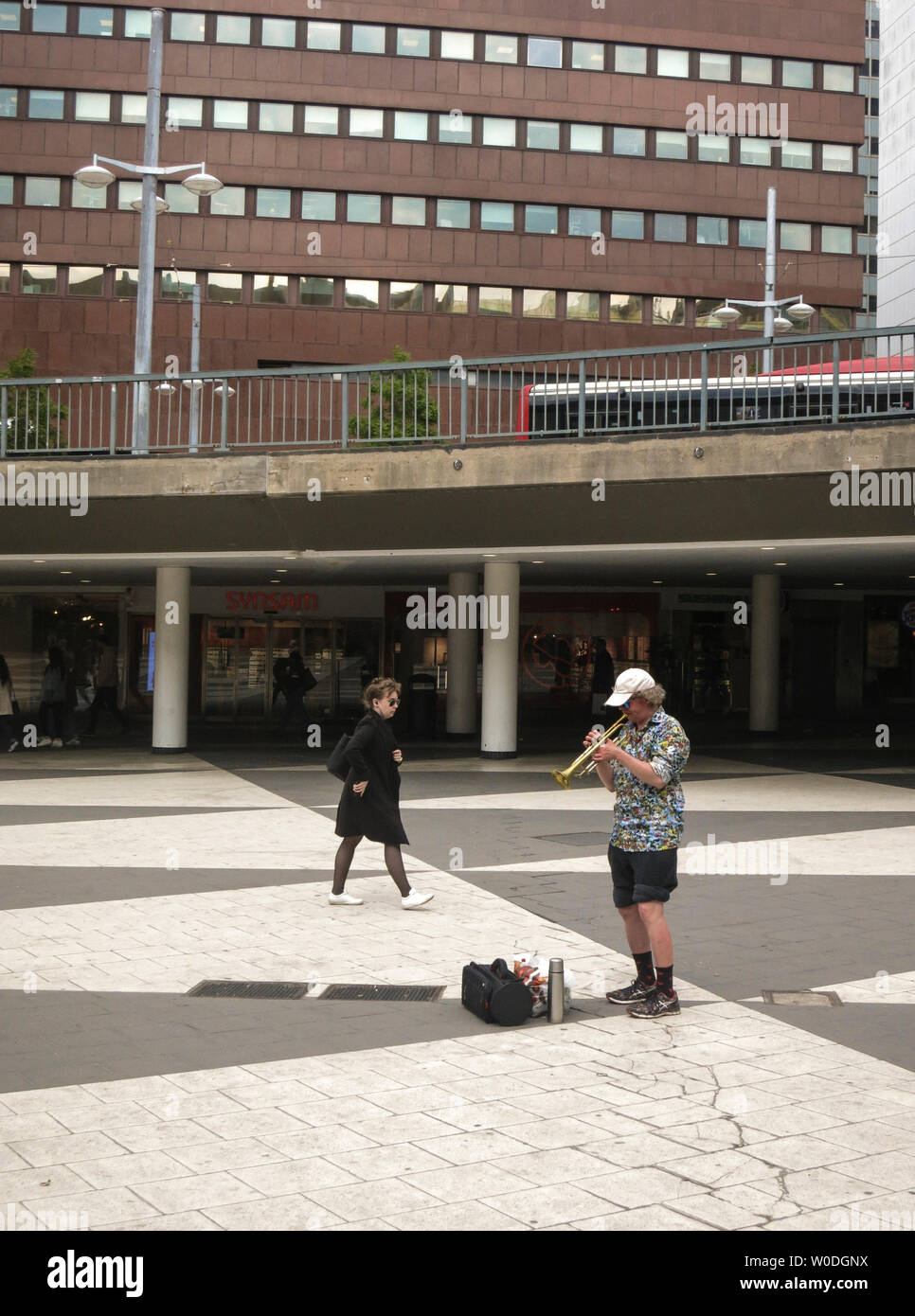 Un hombre solitario en pantalones cortos y tapón reproduce con una trompeta en Sergels torg en Estocolmo, Suecia Foto de stock