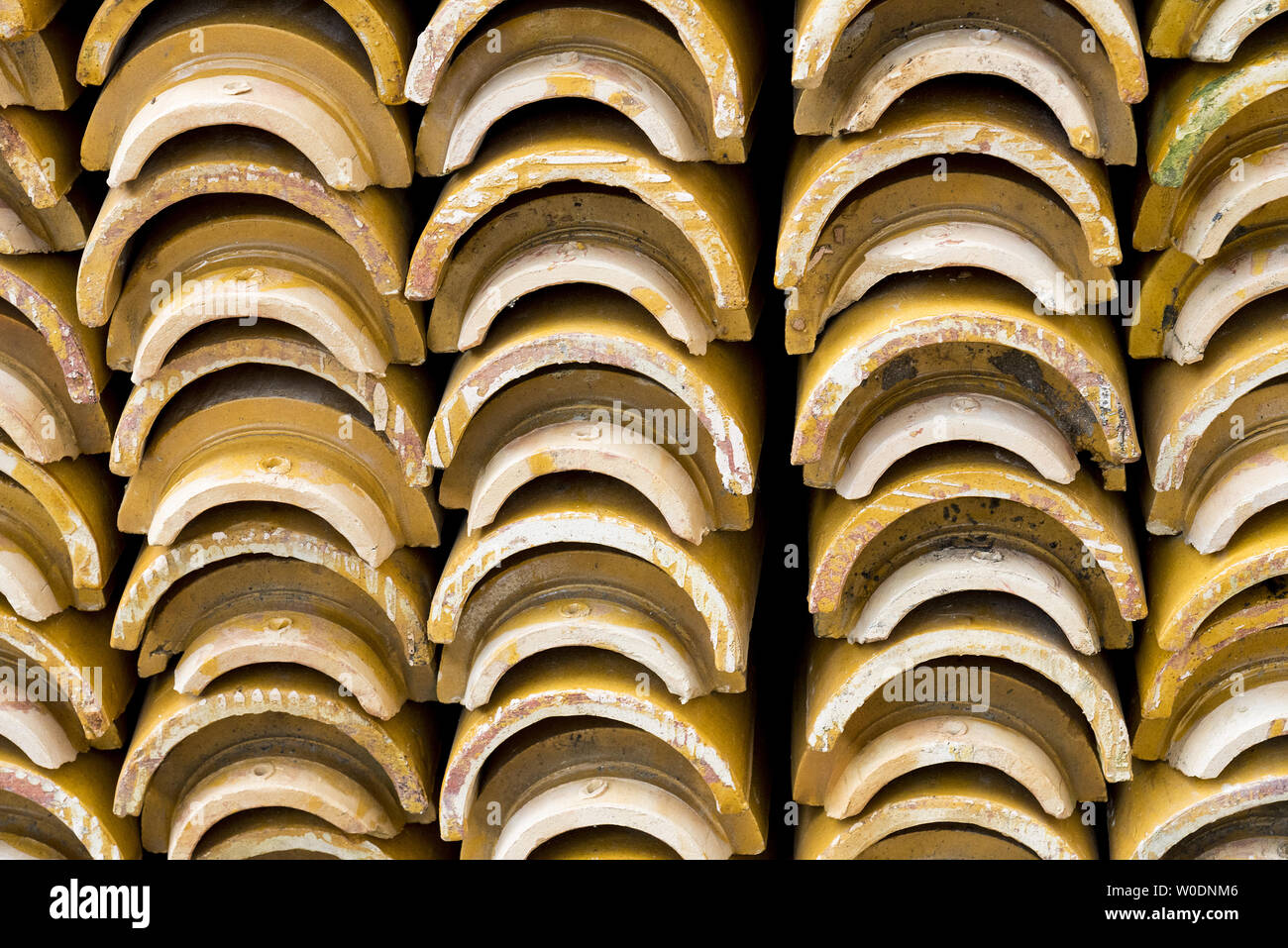 Pilas de amarillo vidriado de cerámica azulejos de techo curvo en un patrón simétrico. Foto de stock