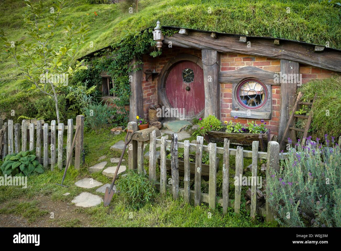 Hobbit cueva con puerta roja, Hobbiton en el shire, ubicación de El Señor de los anillos y el Hobbit Matamata, Waikato, Isla del Norte, Nueva Zelanda Foto de stock