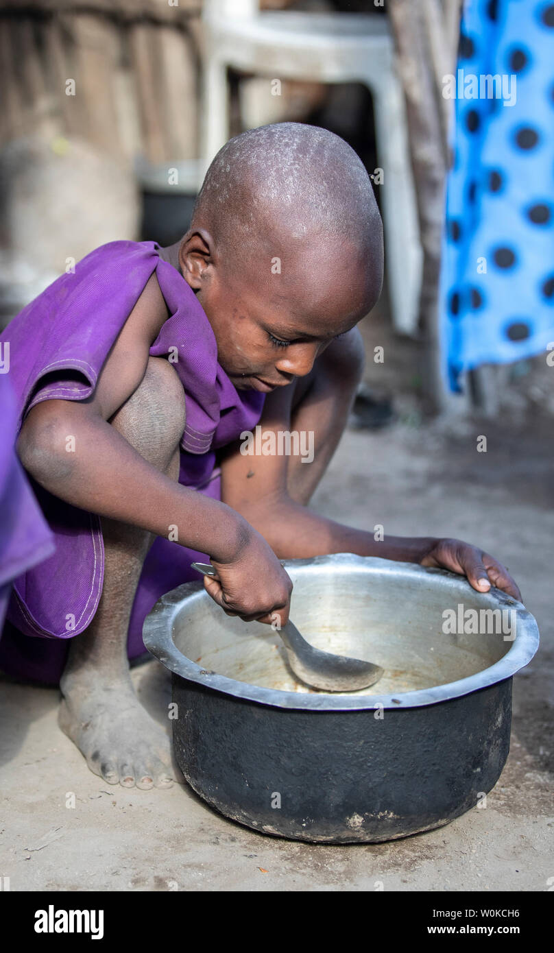 Mismo, Tanzanía, 4 de junio de 2019: el joven niña Maasai raspar restos de  comida fuera una olla para que ella pueda comer más Fotografía de stock -  Alamy