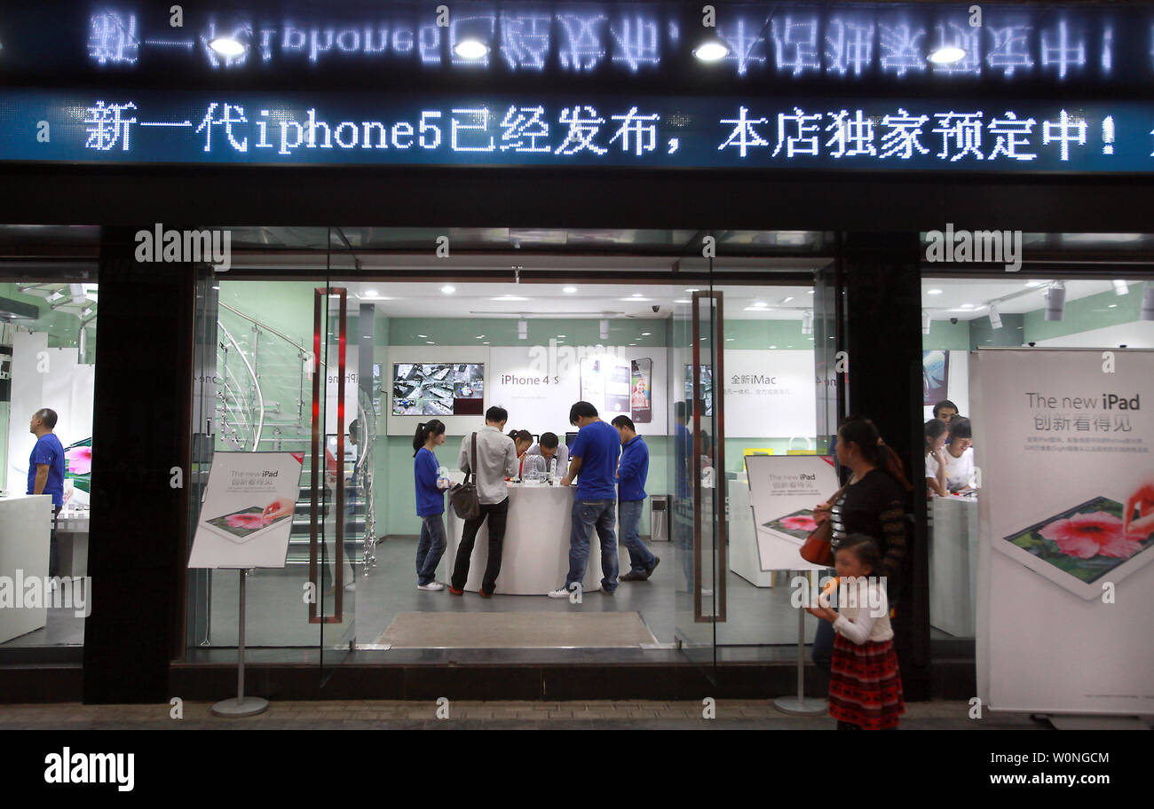 Los empleados chinos vestidos como oficiales de Apple al personal a trabajar en una tienda de informática que pregonaba flagrantemente a sí mismo como un oficial "inteligente Apple Store, los clientes de venta real y 'Gris' los productos de Apple en Kunming, la capital de la provincia de Yunnan, el 24 de septiembre de 2012. Kunming tiene varias tiendas 'Apple' el año pasado de cesar y desistir a despreciar abiertamente las infracciones de copyright y marcas comerciales. En el caso de stands, muchas veces una demostración de fuerza por parte del gobierno para atacar y resolver esos problemas suele ser sólo temporal con el fin de apaciguar a los reclamantes. UPI/Stephen afeitadora Foto de stock