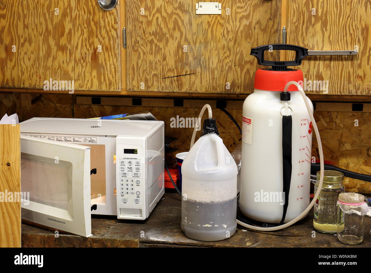 Laboratorio de metanfetamina en un garaje del banco de trabajo consta de una botella de plástico, un pulverizador químico, y tarros de disolventes. Foto de stock