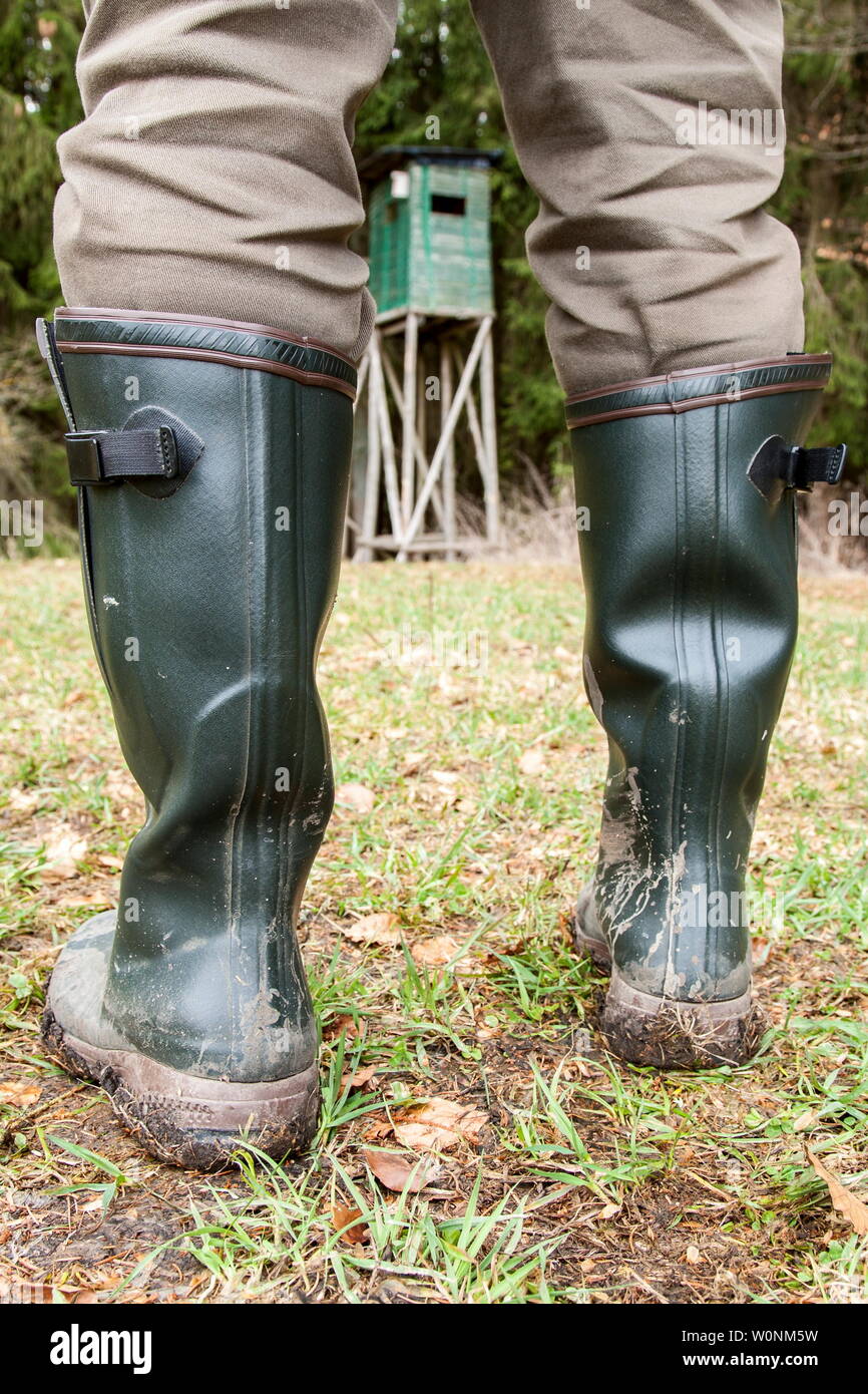 Botas Wellington en la zona de caza, los zapatos. Un cazador de stands con  sus botas de caucho verde sobre un fondo fangoso prado al frente de su  púlpito de caza Fotografía