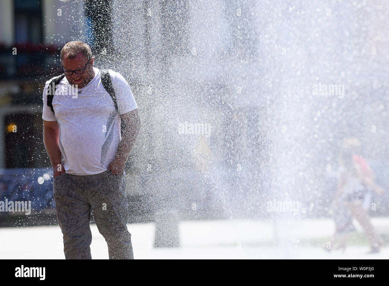 Un hombre se actualiza en una cortina de agua contra incendios pistola  junto a un centro comercial Krakowska durante las altas temperaturas en  Cracovia.Un registro de junio también fue establecido en Polonia