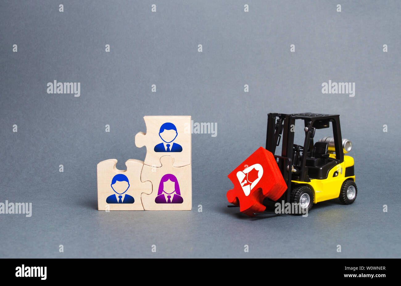 Una carretilla transporta un puzzle rojo a la Asamblea inconclusa del equipo empresarial. Búsqueda, reclutamiento, contratación de personal dirigente. La creación de un eficiente y Foto de stock