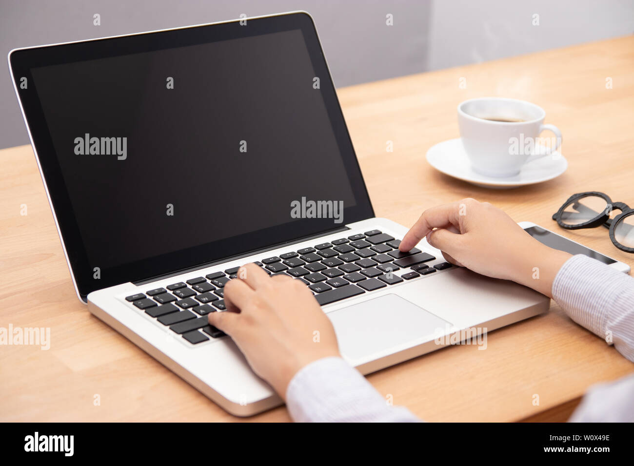 La empresaria trabaja con ordenador portátil, con el dedo con el teclado para escribir. un ordenador portátil con pantalla negra en blanco para copiar el espacio Foto de stock