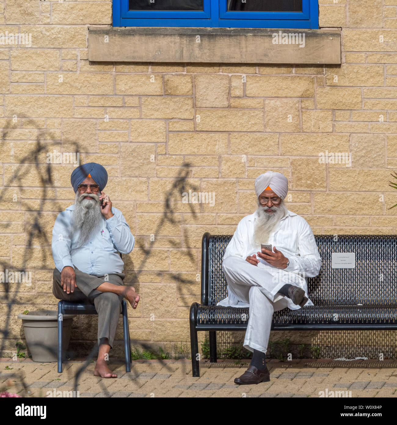 Dos señores sentados fuera Templo Sikh llevar turbantes tradicionales Foto de stock