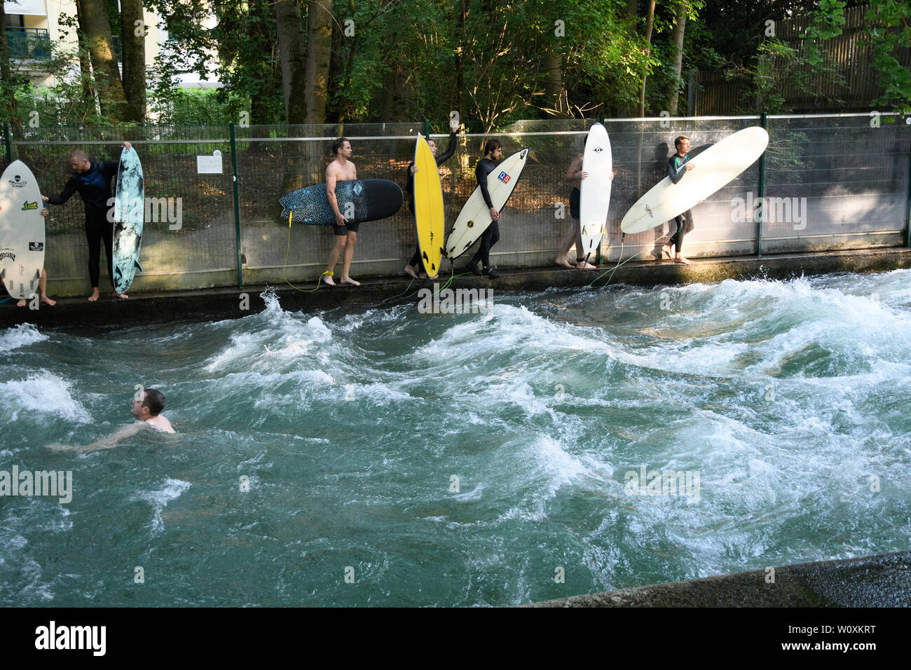 MUNICH, Alemania - Agosto 2018: Surfistas en un tren de ondas estacionarias en un arroyo en el Parque de la ciudad durante la ola de calor. Foto de stock