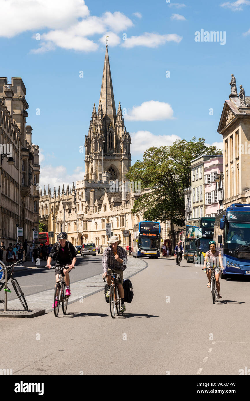 Mirando a lo largo de High St hacia la iglesia de Santa María como los ciclistas en el paseo a lo largo de un hermoso día soleado de verano a la famosa ciudad universitaria de Oxford. Foto de stock