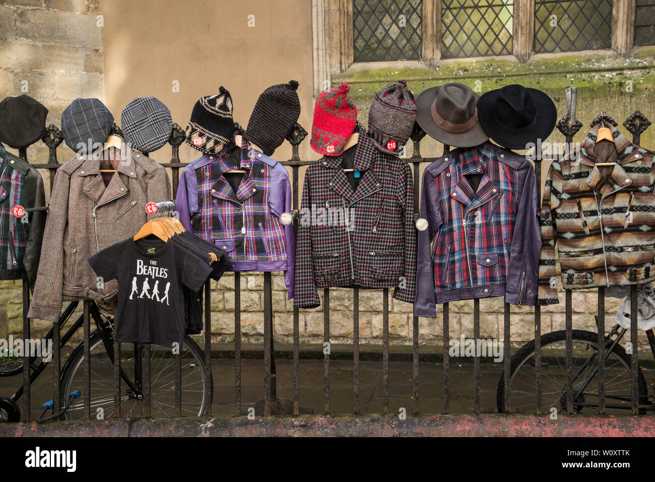 Un vendedor de ropa utiliza las barandillas fuera la gran iglesia de San Andrés al display de su mercadería en el centro de Cambridge, 2019 Foto de stock