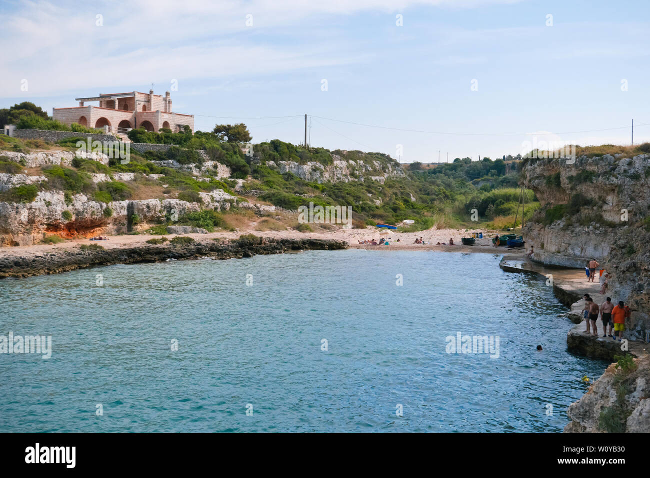 Monopoli, Italia; personas irreconocibles en la playa de la bahía del pescador en el territorio de Monopoli una tarde de verano en el tiempo libre. Foto de stock