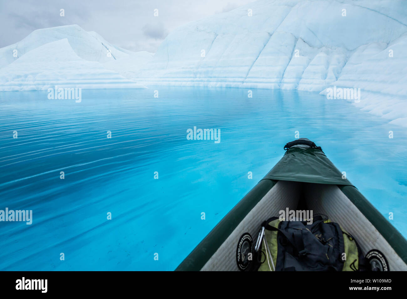 Hasta el Glaciar Matanuska en Alaska una canoa inflable flota sobre un profundo lago azul en la parte superior del glaciar. Foto de stock