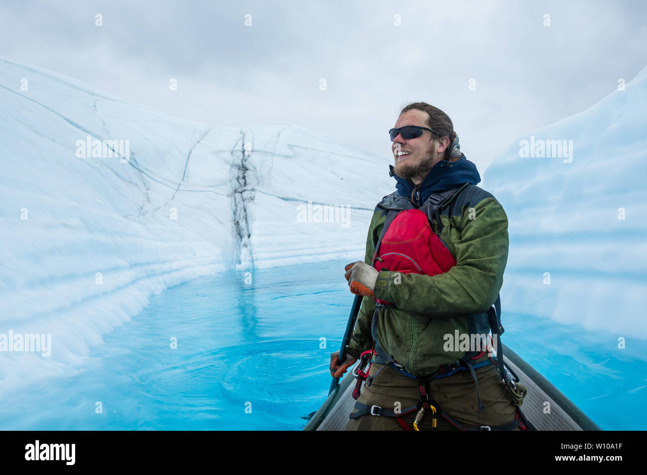 Un supraglacial Lake (lago en la parte superior de hielo glaciar) donde un escalador de hielo ha traído una canoa inflable para remar a través de las profundas aguas azules Foto de stock