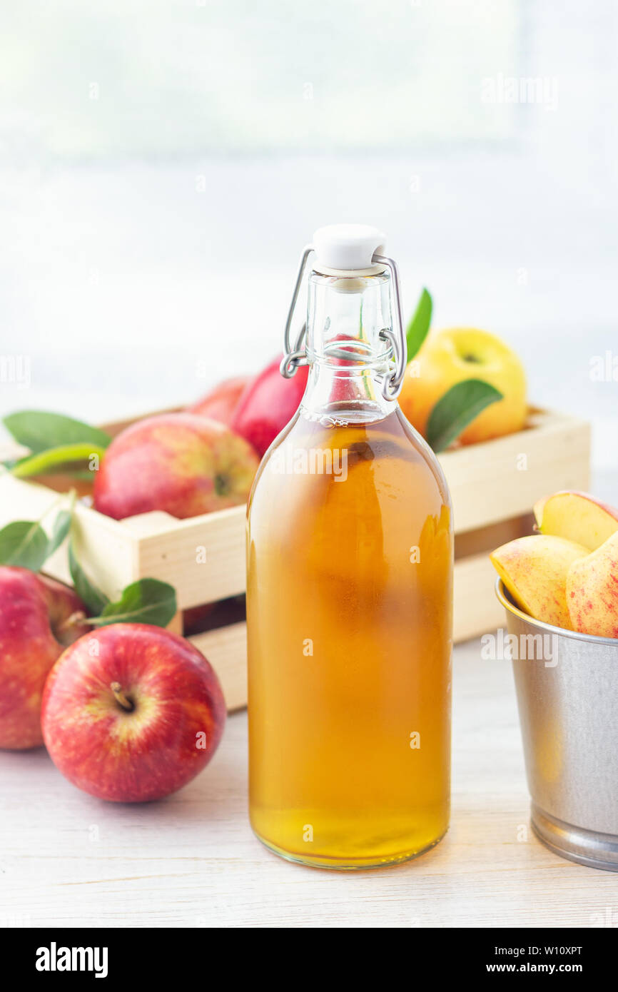 Los alimentos orgánicos saludables. El vinagre de sidra de manzana en botella de vidrio y frescas manzanas rojas sobre un fondo claro. Foto de stock