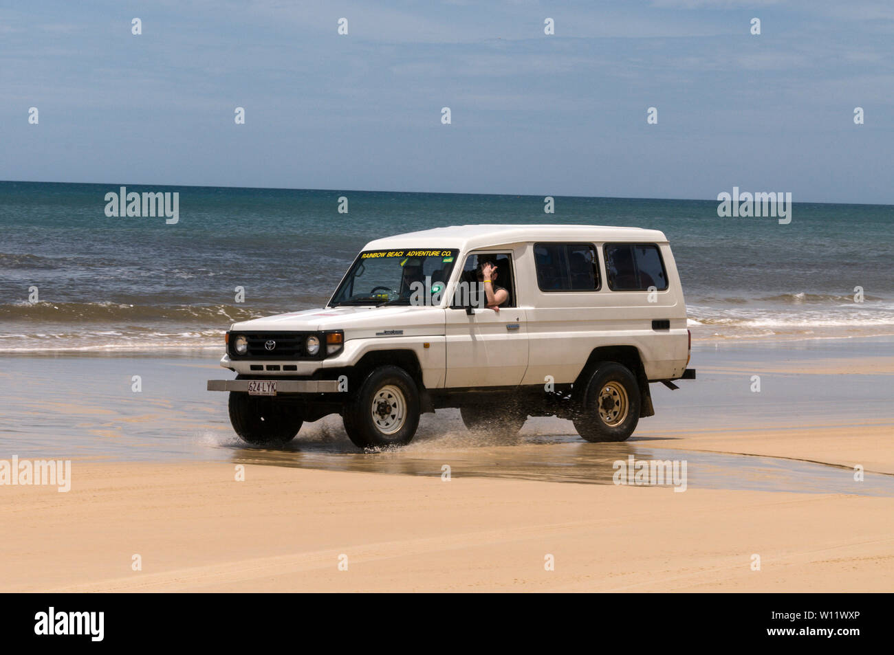 Un joven turista llevando 4WD en la autopista de 75 millas a lo largo de arena en la Isla Fraser, Queensland, Australia, frente al Océano Pacífico Sur. Isla Fraser Foto de stock