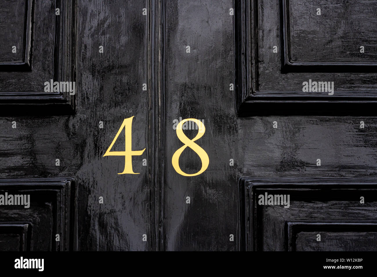 Casa número 48, con los cuarenta y ocho pintadas en oro sobre un antiguo de madera pintadas de negro de la puerta delantera Foto de stock