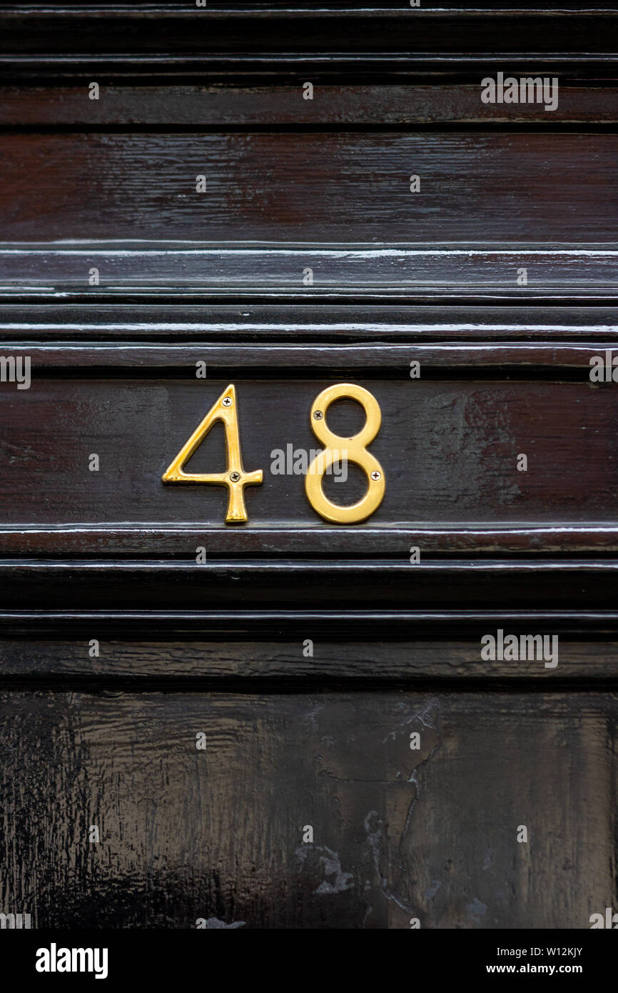 Casa número 48, con los cuarenta y ocho en metal pintado negro dígitos sobre una antigua puerta de madera Foto de stock
