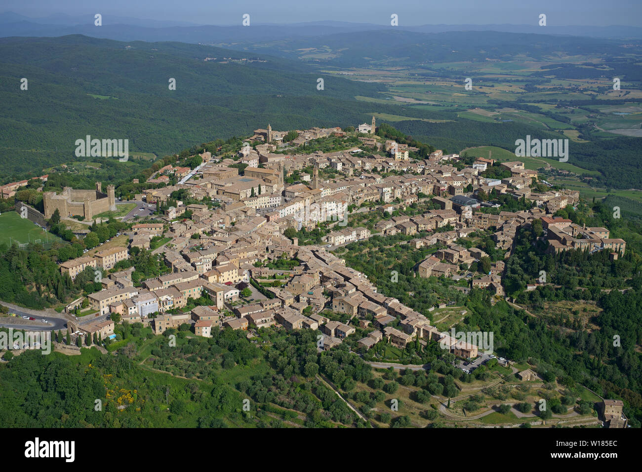 VISTA AÉREA. Ciudad medieval en la cima de una colina que domina las tierras de labranza de Val d'Orcia. Montalcino, Provincia de Siena, Toscana, Italia. Foto de stock