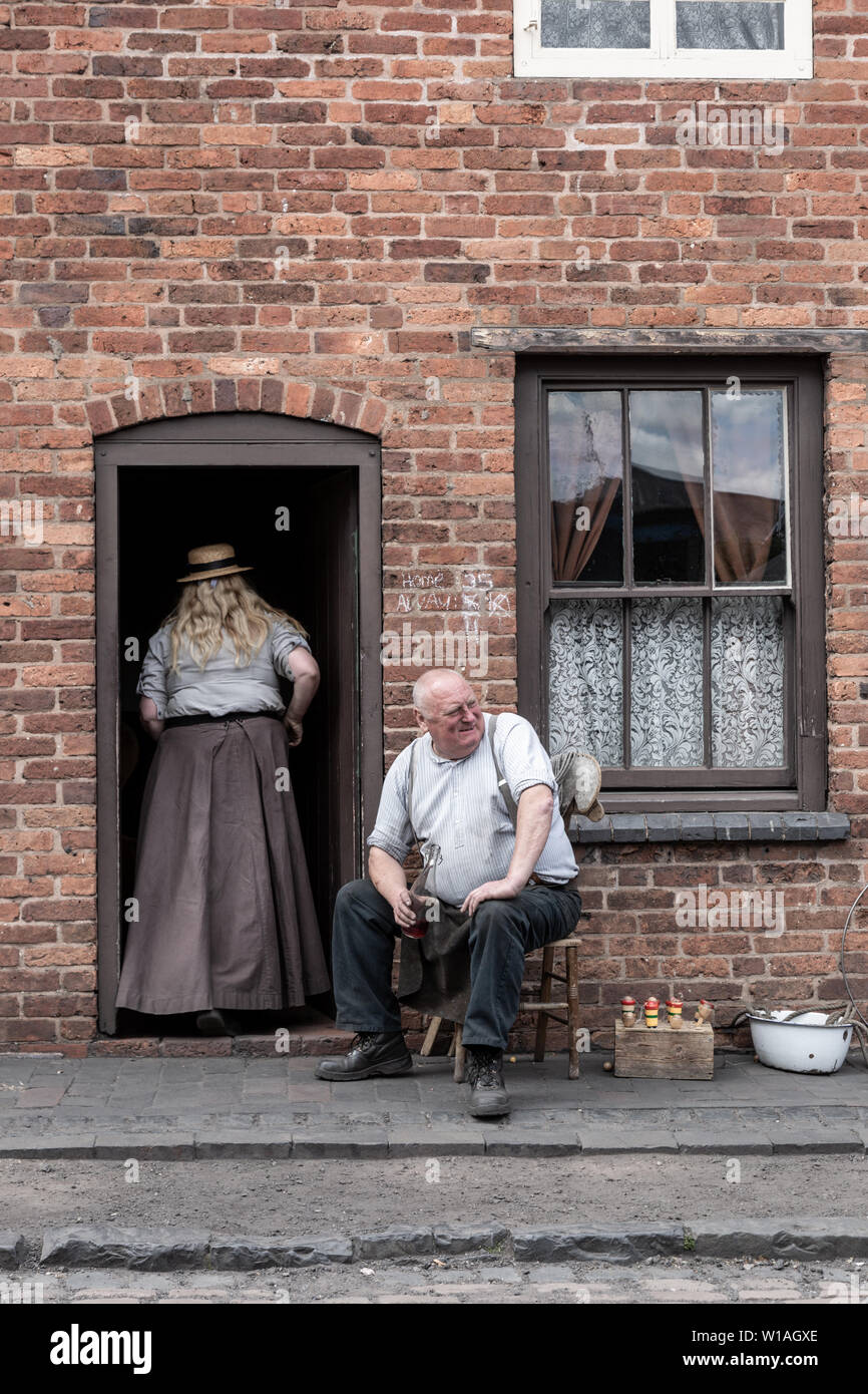 Dos personas vestidas con ropas de estilo Eduardiano fuera de una casa adosada, Black Country Living Museum, Dudley UK Foto de stock