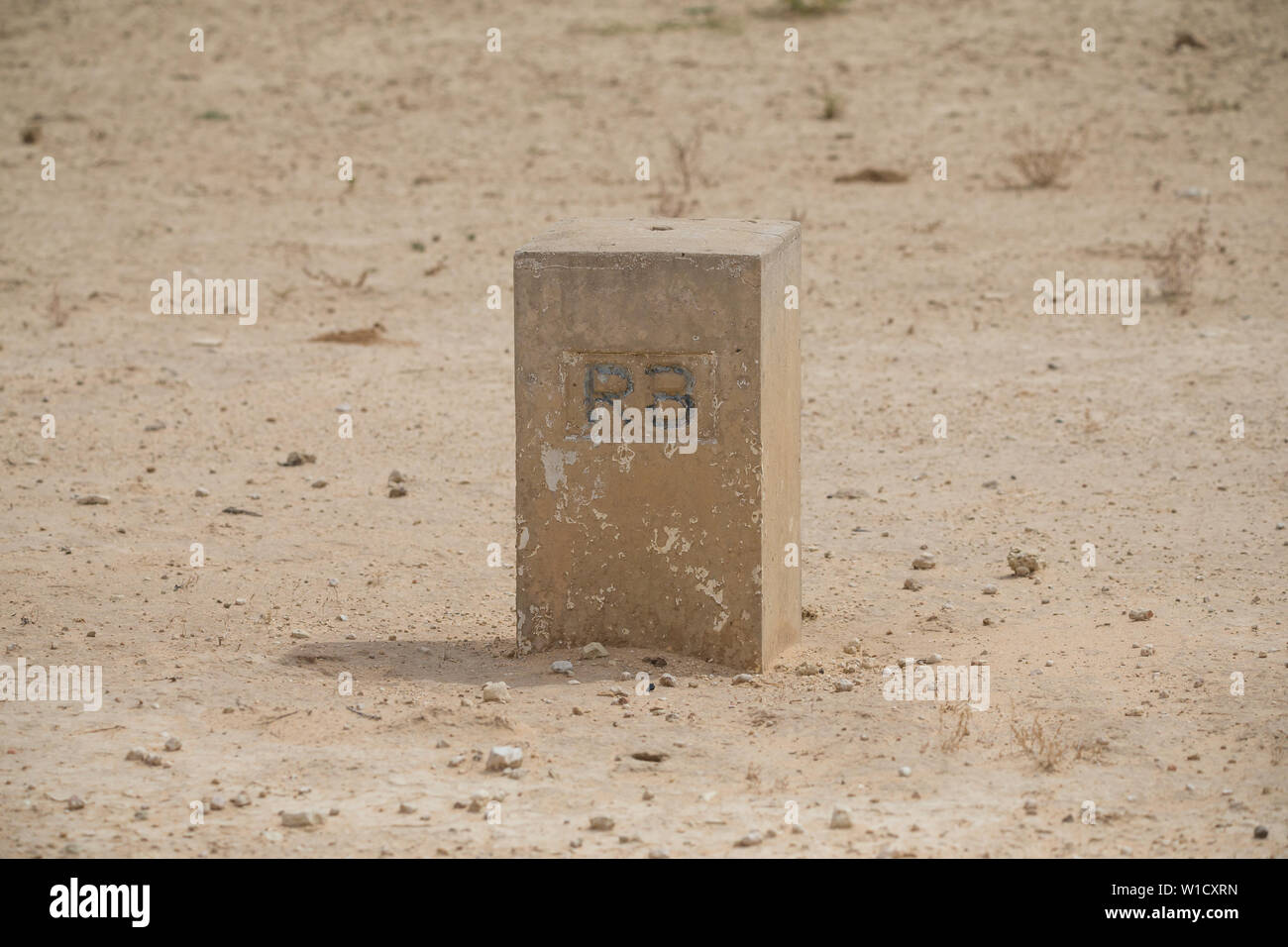 Un marcador de piedra o hito que marca la frontera de la República de Botswana en la arena del desierto de Kalahari en el Parque Transfronterizo Kgalagadi, Sudáfrica Foto de stock