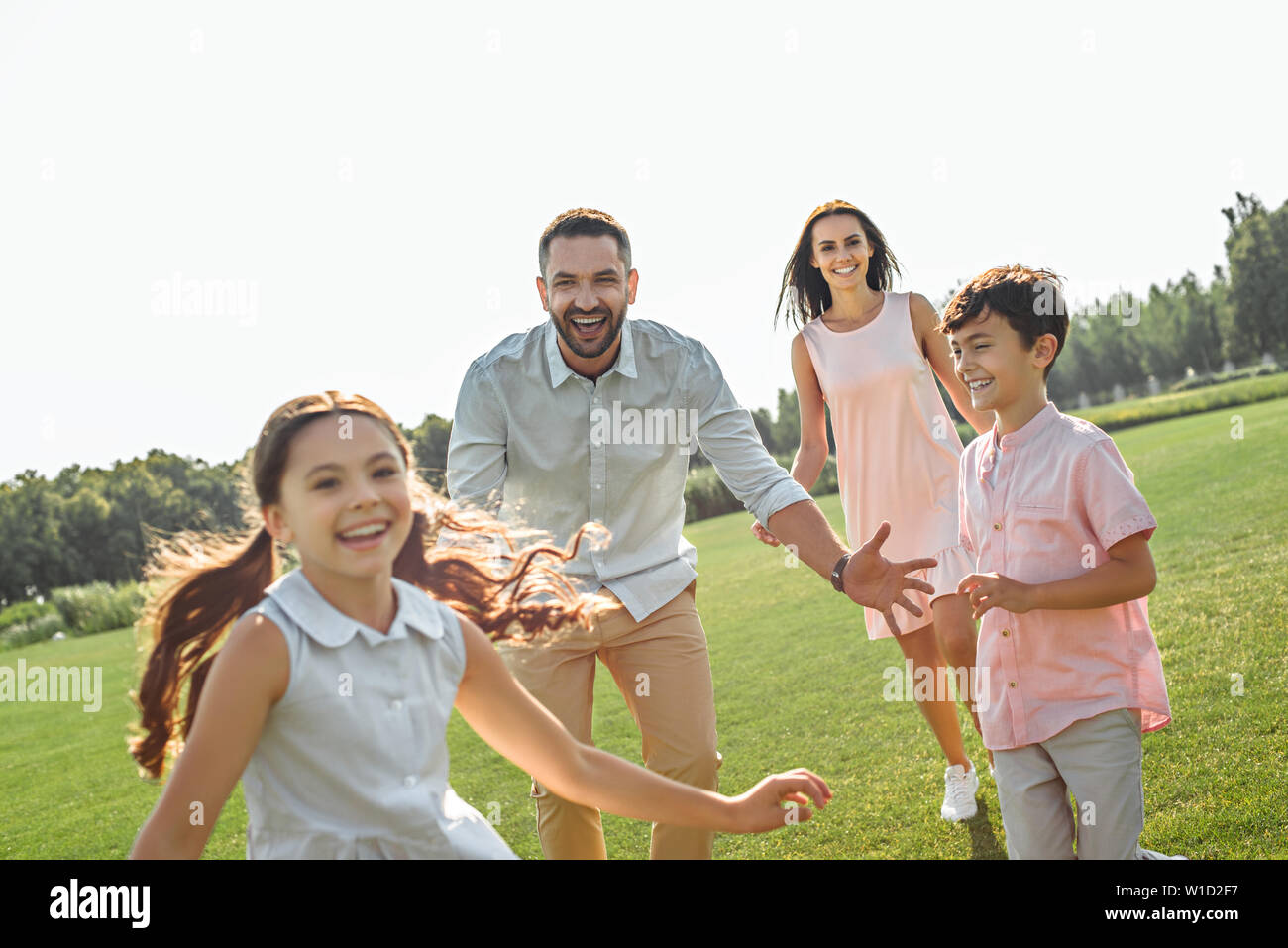 Te voy a atrapar feliz padre jugando con sus hijos y sonriendo mientras pasas tiempo libre con la familia al aire libre. Actividades de fin de semana Foto de stock